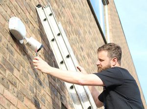 CCTV camera being installed on brick wall