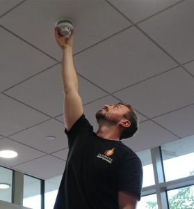 fire alarm engineer installing fire alarm to ceiling